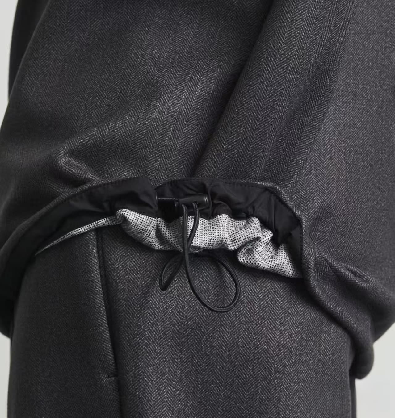 Dark grey herringbone fabric with an adjustable black drawstring and toggle at the bottom hem.