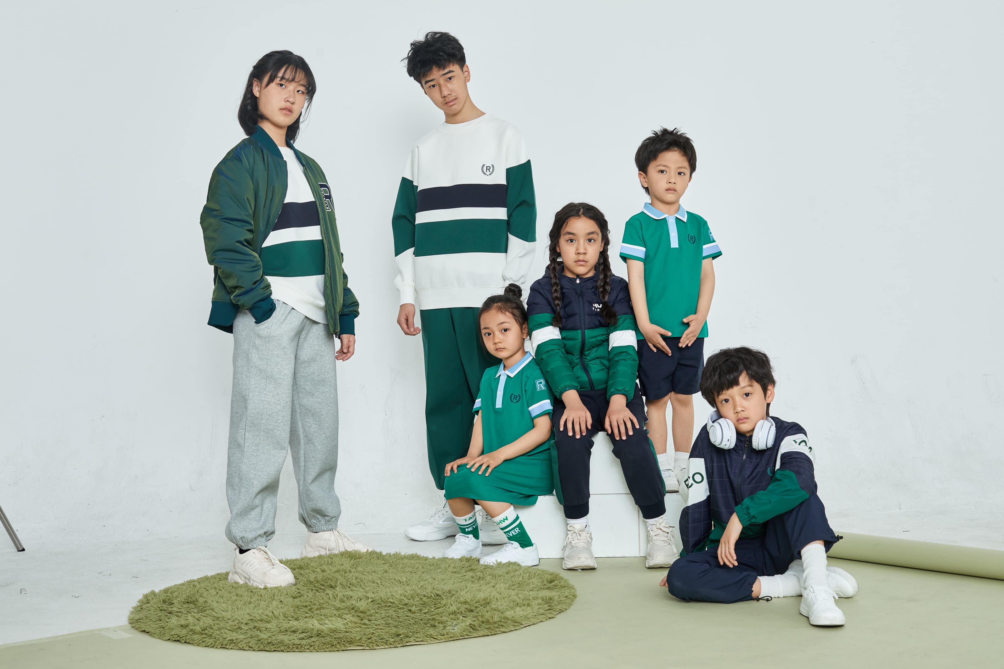 Six youth modeling coordinated green, white, and navy blue sportswear against a white background.