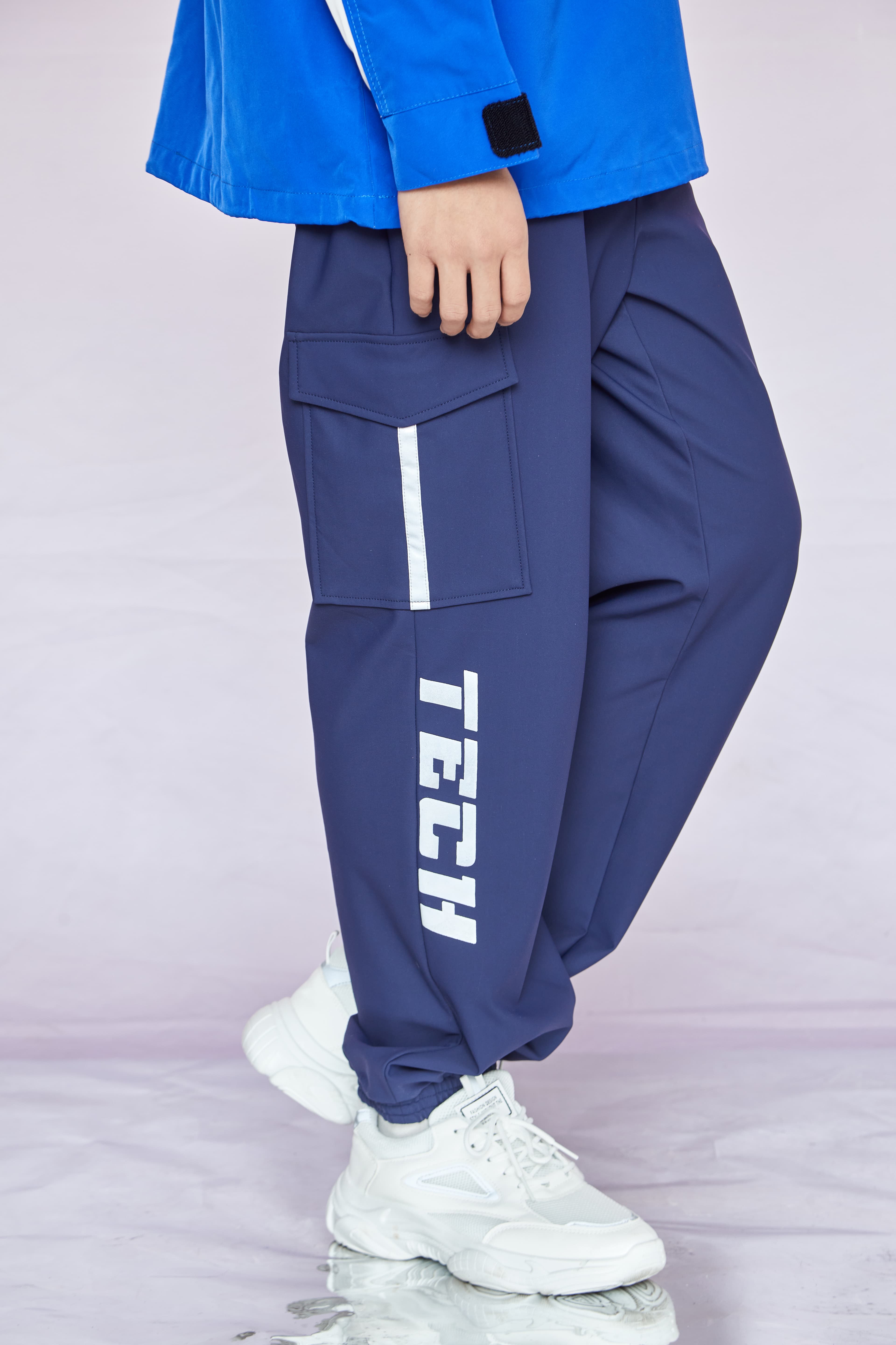 Navy blue cargo pants with white 'TECH' text on the leg and white athletic sneakers.